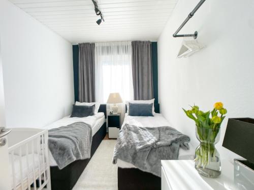 a room with two beds and a vase of flowers at M-Style 01 Apartment mit Terrasse und Gasgrill, 24h Self-Check-In, Free Parking, Netflix in Nuremberg