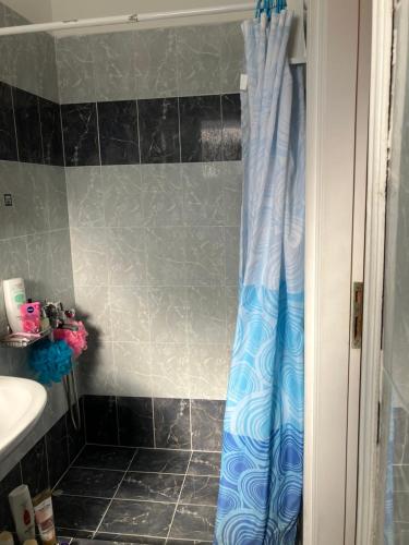 łazienka z prysznicem z niebieską zasłoną prysznicową w obiekcie VOULA'S HOUSES w mieście Neo Karlowasi