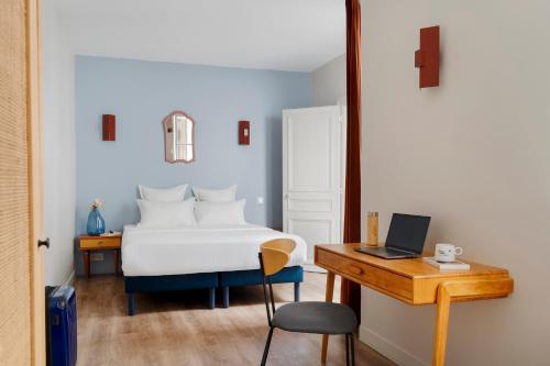 a bedroom with a bed and a desk with a laptop at Edgar Suites Grands Boulevards - Boulanger in Paris