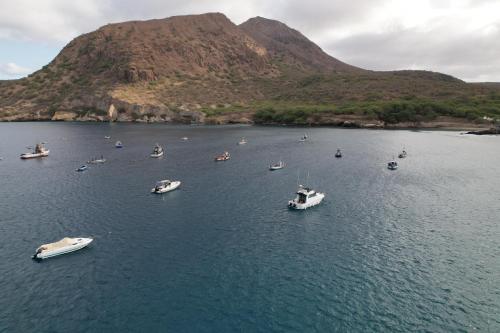 a group of boats in a body of water with a mountain at Hotel Viajante in Tarrafal