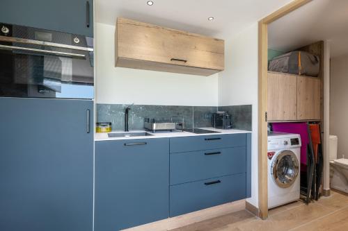 a kitchen with blue cabinets and a washer and dryer at Prunières - Joli T2 dans la Haute-Loire in Saint-Pal-de-Mons