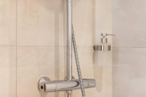 a shower with a shower handle in a bathroom at Le Bohémien - Résidence Hestia in Saint-Étienne