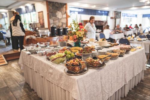 una mesa buffet con comida en ella con gente en un restaurante en Patagonia Plaza Hotel en San Martín de los Andes