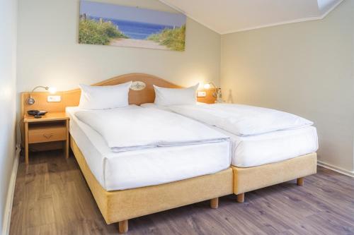 a bedroom with two beds and a table with a picture at Hotel Dänischer Hof Altenholz by Tulip Inn in Altenholz