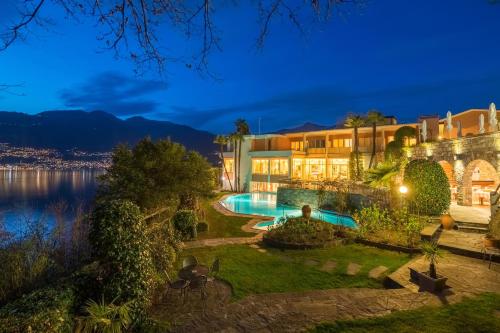 a mansion with a swimming pool at night at Bellavista Swiss Quality Hotel in Vira