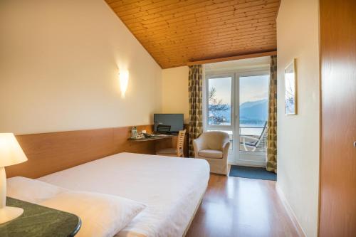 a hotel room with a bed and a desk and a window at Bellavista Swiss Quality Hotel in Vira