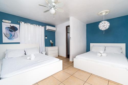 twee bedden in een kamer met blauwe muren bij Casamares Private Room Mar with Pool and Jacuzzi 5 min to Boqueron and Beaches in Cabo Rojo