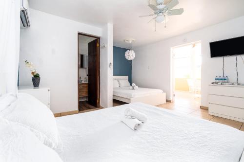 a white bedroom with a white bed and a living room at Casamares Private Room Mar with Pool and Barbecue 5 min to Boqueron and Beaches in Cabo Rojo