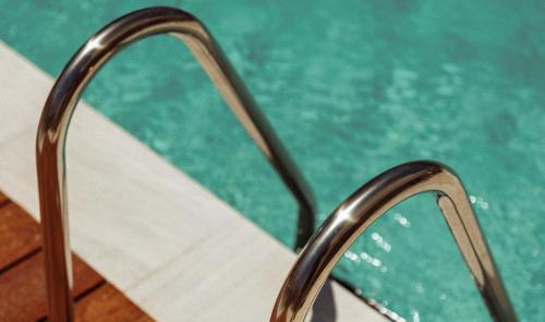 een metalen leuning naast een zwembad bij Regency Boutique Hotel Holiday Suites in Paphos City