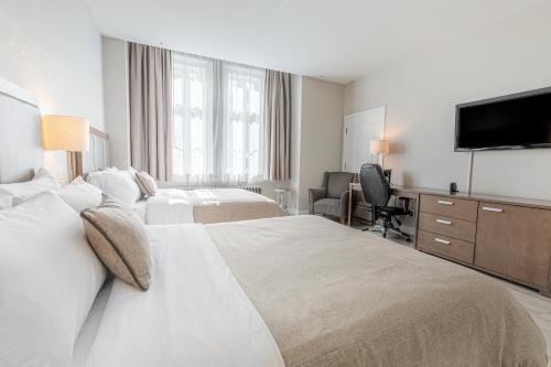 a hotel room with two beds and a flat screen tv at Hotel Montfort Nicolet in Nicolet