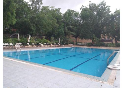 a large blue swimming pool with chairs and trees at Juba Landmark Hotel in Juba