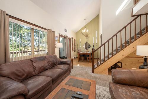 a living room with a leather couch and a staircase at Twin Rivers Vasquez 3 by Stay Winter Park in Fraser