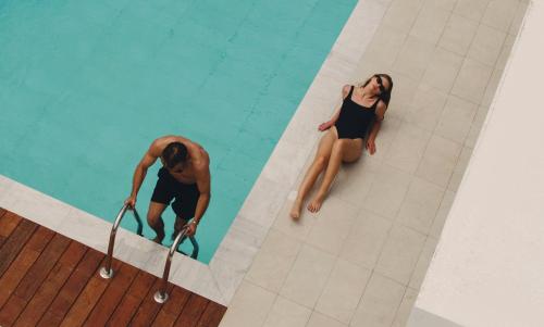 Regency Boutique Hotel Holiday Suites في بافوس: رجل وامرأة يقفان في مسبح