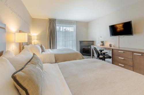 a hotel room with two beds and a desk at Hotel Montfort Nicolet in Nicolet