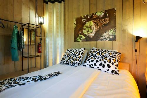 1 dormitorio con cama blanca y almohadas de leopardo en Glamping Safarilodge 'Grutte Fiif' met airco, extra keuken op veranda en privé achtertuin, en Grou
