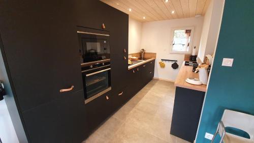 - une cuisine avec des placards noirs et un évier dans l'établissement CHALET LES PRIMEVÈRES 4 Étoiles, à Gerbépal