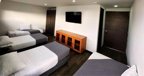 a hotel room with two beds and a flat screen tv at Hotel Expo Hotel Ferial in Bogotá