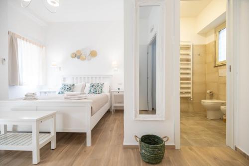 een witte slaapkamer met een bed en een spiegel bij Light Garden in Taormina
