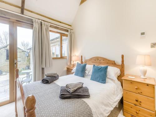 a bedroom with a bed with blue pillows and a window at Olive Barn in Witheridge
