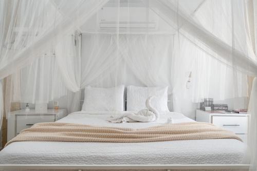 - une chambre blanche avec un grand lit recouvert d'un cygne dans l'établissement ATOAS - Lovely Vacation Retreat with Pool and Jacuzzi 5 min to Boqueron and Beaches, à Cabo Rojo