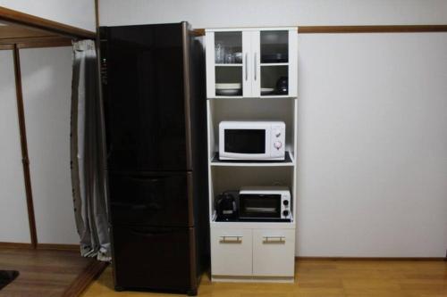 a kitchen with a black refrigerator and a microwave at JR福井駅東口から徒歩7分(550m)。一棟貸切民泊トリプレッツ in Fukui