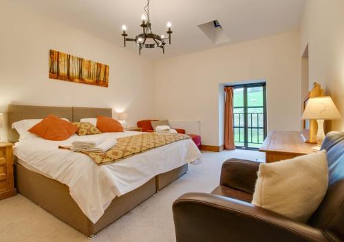 a bedroom with a large bed and a chair at Bythynnod Aderyn Cottages in Cemmaes
