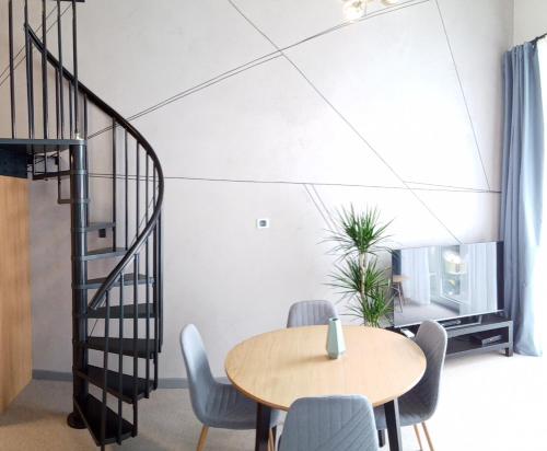 a dining room with a table and chairs and a spiral staircase at Wroclove Airport Loft in Wrocław