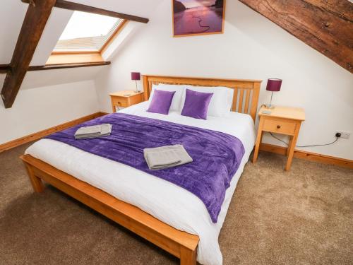 a bedroom with a large bed with a purple blanket at Y Felin in Haverfordwest
