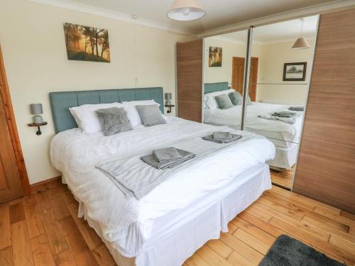 a bedroom with a large white bed and a mirror at Ty Mawr in Haverfordwest