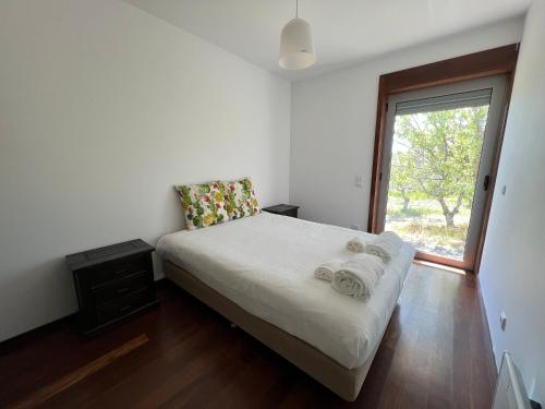 a bedroom with a bed with white sheets and a window at Villa Martins in Lagoaça