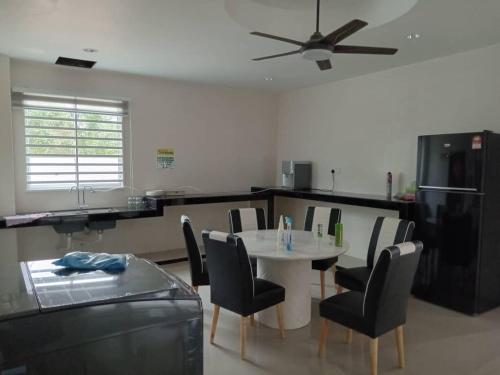 a kitchen with a table and chairs and a ceiling fan at EMERALD VILLA HOMESTAY DUNGUN in Batu Lima