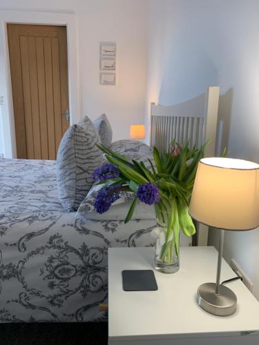 a bedroom with a bed with a table with a vase of flowers at Rossendale Holiday Cottages & Spa in Rossendale