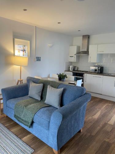a blue couch in a living room with a kitchen at Rossendale Holiday Cottages & Spa in Rossendale