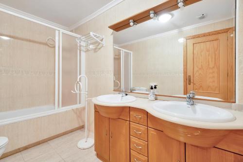 Un baño con dos lavabos y una ducha. en Casa en playa con piscina Novamar, en Santa Pola