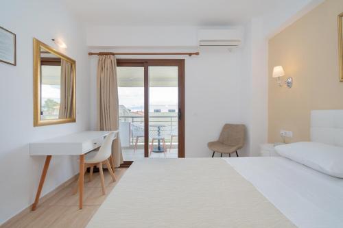 a bedroom with a bed and a desk and a window at Star Paradise Hotel in Neos Marmaras