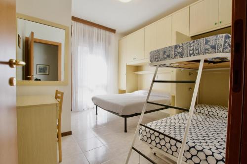 Cette petite chambre comprend des lits superposés et un lit. dans l'établissement Residence Madrid, à Lido di Jesolo