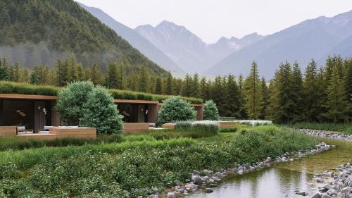 un edificio junto a un río con montañas en el fondo en nancy's Holiday Homes Dolomites, en Rasun di Sotto
