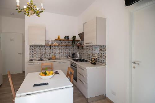 a kitchen with white cabinets and a bowl of fruit on a table at Light Garden in Taormina