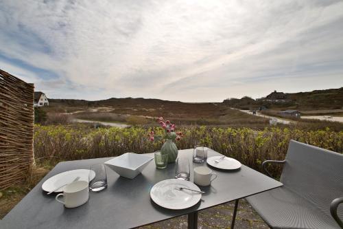 a table with plates and a vase of flowers on it at ApartHotel Seepferdchen in Hörnum