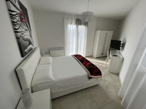 a white bedroom with a bed and a window at Casa Vacanze Le Tre Scimmiette in Paterno