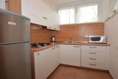 リニャーノ・サッビアドーロにあるVillaggio Lauraのキッチン(白いキャビネット、ステンレス製の冷蔵庫付)