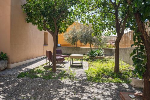 a patio with a table and a chair under two trees at Light Garden in Taormina