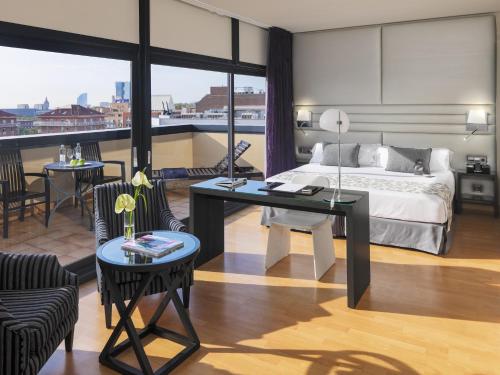 a hotel room with a bed and a desk and chairs at H10 Marina Barcelona in Barcelona