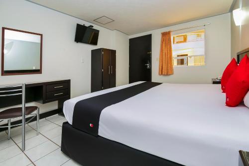 a bedroom with a large white bed and a television at Capital O Hotel Victoria Morelia in Morelia