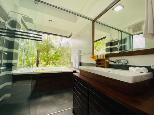 een badkamer met een bad, een wastafel en een spiegel bij The Glenrock in Belihul Oya