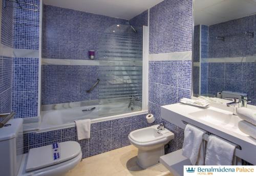 Baño de azulejos azules con aseo y lavamanos en Benalmadena Palace Spa, en Benalmádena