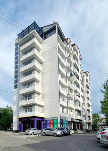 a tall white building with cars parked in front of it at Kate's cozy apartment in Kutaisi