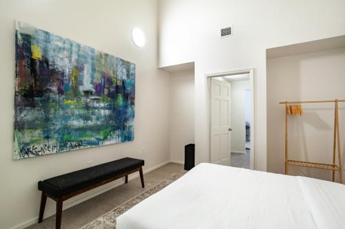 a bedroom with a white bed and a painting on the wall at Historic Downtown Loft with Modern Flare in Knoxville