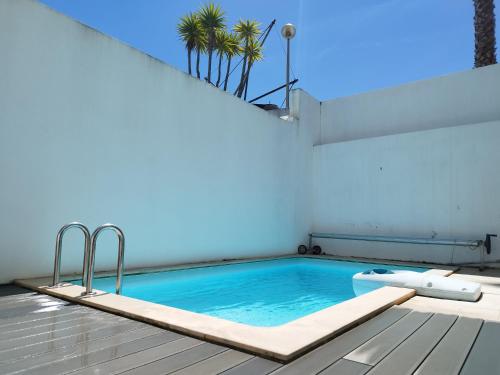 a swimming pool with palm trees on a building at Sunset Street Beach house in Lourinhã