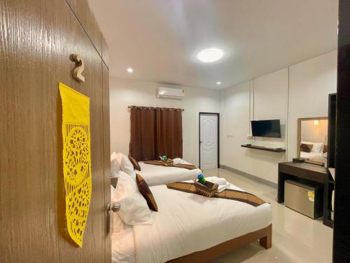 a hotel room with two beds and a television at บ้านกาญจน์ เชียงราย Baan Kan Chiang Rai in Chiang Rai